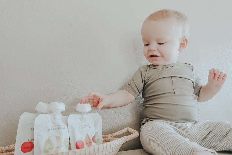 Baby playing with baby food packet