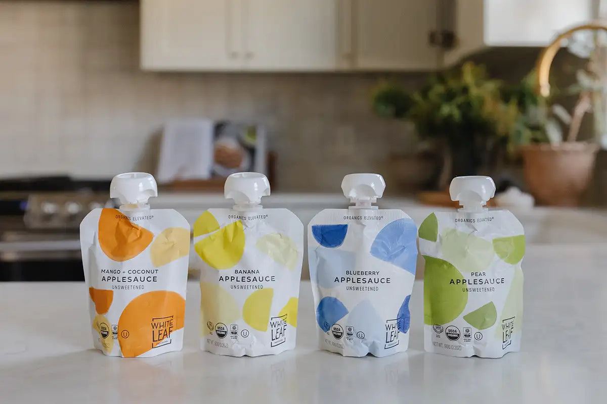 Four pouches of organic applesauce baby food on a kitchen counter